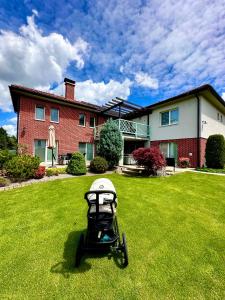 a baby stroller sitting in the grass in front of a house at Penzión Lili in Opatovce nad Nitrou