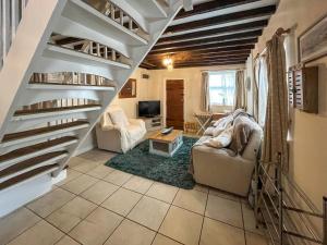 a living room with stairs and a couch and a tv at Bacchus Cottage - Uk51964 in Sutton on Sea