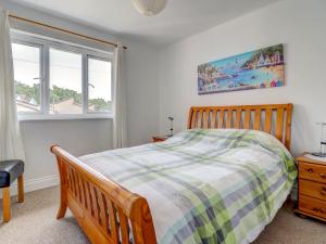 a bedroom with a wooden bed and two windows at Thistle Cottage in Ryde