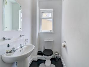 a white bathroom with a toilet and a sink at Thistle Cottage in Ryde