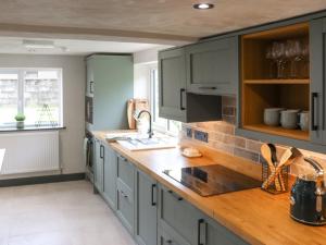 a kitchen with gray cabinets and a wooden counter top at Brynawel in Maenclochog