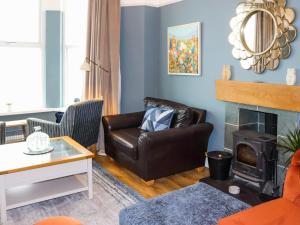 a living room with a leather couch and a fireplace at Bay View - Uk52077 in Criccieth