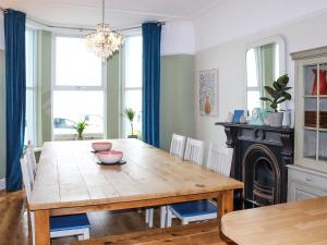 a dining room with a wooden table and blue curtains at Bay View - Uk52077 in Criccieth +25 photos