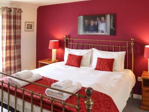 a bedroom with a large bed with red walls at The Quarry Stables in Cheddar
