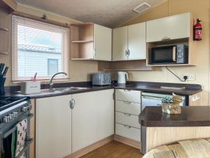 a kitchen with white cabinets and a microwave at Valley View - Uk52130 in Oakmere