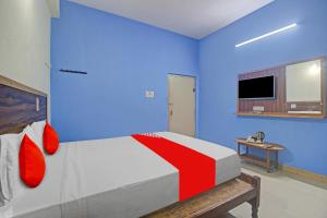 a bedroom with blue walls and a bed with red pillows at Hotel O Satya Inn in Karīmnagar