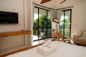 a bedroom with a bed and a tv and a balcony at Blue Sky Seaview in Haad Yao