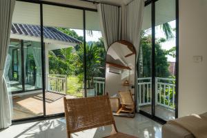 a room with large windows and a chair on a balcony at Blue Sky Seaview in Haad Yao