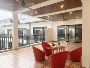a lobby with red chairs and tables and windows at Baan Phu Place in Ban Suan