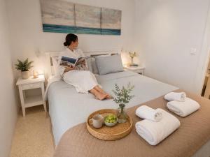 a woman sitting on a bed reading a book at Ni&Gio Sterna 6 in Parikia