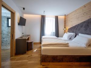 a hotel room with two beds and a television at al Ritrovo - rooms & more in Andalo