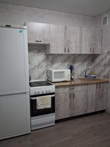 a kitchen with a white stove and a microwave at Ткачёва in Pavlodar +6 photos
