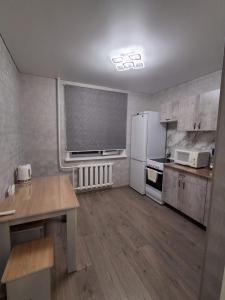 a kitchen with a white refrigerator and a table at Ткачёва in Pavlodar