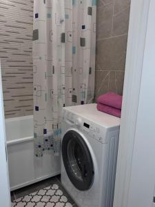 a washing machine in a bathroom with a shower curtain at Ткачёва in Pavlodar
