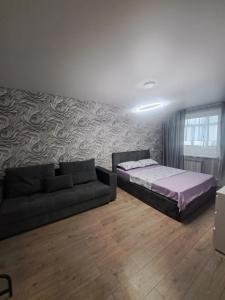 a living room with a bed and a couch at Ткачёва in Pavlodar