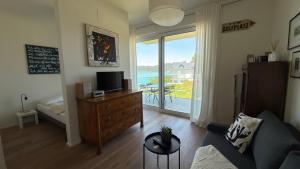 a living room with a couch and a tv on a dresser at Hermitage Apartment E03B - Seeblick & Zugang in Maria Wörth