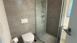 a bathroom with a toilet and a glass shower at Hermitage Apartment E03B - Seeblick & Zugang in Maria Wörth +12 photos