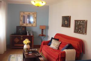 a living room with a red couch and a tv at Bela Vista in Lourinhã