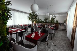 a restaurant with red tables and chairs and plants at Hôtel Elite in Sion