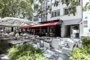 a restaurant with tables and chairs and an umbrella at Hôtel Elite in Sion