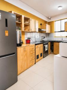 a kitchen with wooden cabinets and a stainless steel refrigerator at Family Surf Chicama in Puerto Chicama