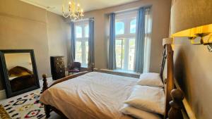 a bedroom with a bed with a mirror and windows at Palace View Apartment in Buxton