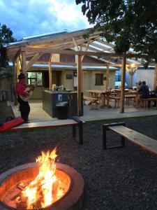 a man playing guitar in front of a fire pit at Camping Yellow Plum in Puerto Natales