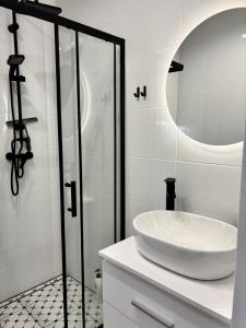 a bathroom with a sink and a glass shower at WOW Apartament in Białystok