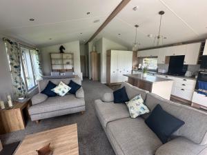 a living room with two couches and a kitchen at Atlantic Breeze, Mullacott Park in West Down