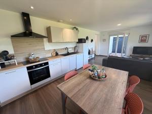 a kitchen and living room with a wooden table and chairs at Au fil de la Blies in Bliesbruck