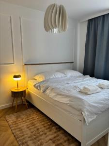 a white bed in a bedroom with a lamp on a table at WOW Apartament in Białystok