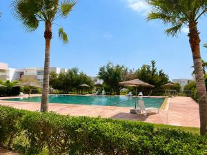 a swimming pool with palm trees and a swing at Nour House Imi Ouaddar in Agadir nʼ Aït Sa