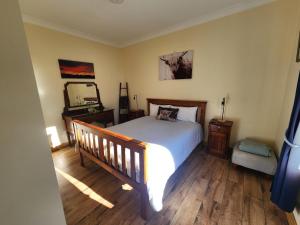 a bedroom with a bed and a dresser and a mirror at Ruby's Cottage Farm Stay in Port Arthur