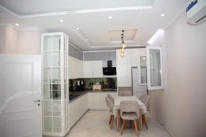 a white kitchen with a table and chairs at Miri House in Domje
