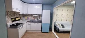 a kitchen with white cabinets and a sink and a chair at Liz House in Incheon +3 photos