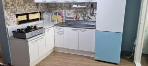 a kitchen with white cabinets and a sink and a refrigerator at Liz House in Incheon