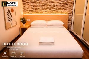 a bedroom with a bed with white sheets and a window at H Hotel in Segamat