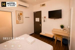 a hotel room with a bed and a desk and a television at H Hotel in Segamat +1 photo