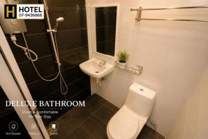 a bathroom with a toilet and a sink and a shower at H Hotel in Segamat