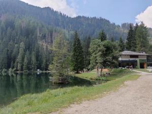 a path next to a lake with a building at Casa Shabby - Comfortable family apartment near the slopes - Confortevole appartamento per famiglie vicino alle piste in Marilleva