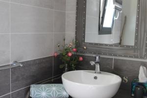 uma casa de banho com lavatório, espelho e flores em Au Fil des Cévennes em Saint-Jean-de-Maruéjols-et-Avéjan