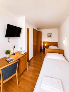 a room with two beds and a desk and a tv at Hotel Alpenblick in Klosters +7 photos