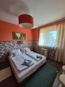 a bedroom with orange walls and a bed with towels on it at Ország Apartmanház in Zalakaros