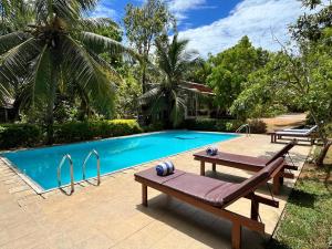 a swimming pool with two wooden benches next to it at The Rock Yala in Yala