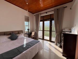 a bedroom with a bed and a sliding glass door at Oli Villa in Belihuloya