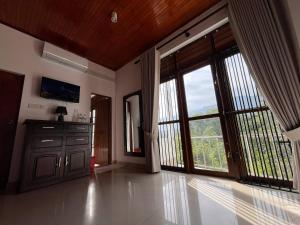 a large room with large doors and windows with a view at Oli Villa in Belihuloya
