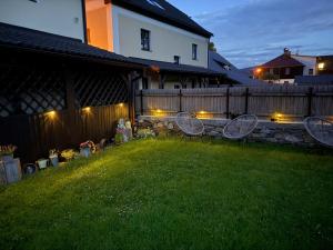 a yard with a fence and some chairs in the grass at Avama - apartmány Srní in Srní