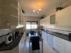 a kitchen with white cabinets and black counter tops at Casa Boa Nova Valadares in Valadares +13 photos