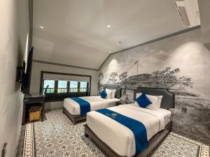 a bedroom with two beds and a painting on the wall at KunKin Boutique Garden Hue in Thôn Dương Xuân Hạ