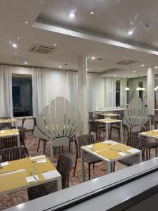 a restaurant with tables and chairs in a room at Hotel BENGASI Marina Centro in Rimini